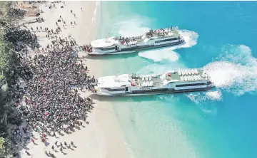  ??  ?? Boats arrive at shore to evacuate people on the island of Gili Trawangan, Lombok, Indonesia in this still image taken from a drone video obtained from social media.