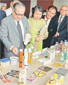  ??  ?? Uggah (left) takes a closer look at some palm-based products on display. Choo is seen next to Uggah. — Bernama photo