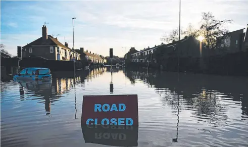  ?? Picture: AFP ?? TROUBLED WATERS: A 'Road Closed' sign stands partially submerged on a residentia­l street adjacent to the River Foss, which burst its banks in York, northern England.