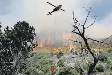  ?? Photograph­s by Gary Coronado Los Angeles Times ?? A HELICOPTER crew battles the Ferguson fire Monday along El Portal Road, a key route into Yosemite. The blaze, which killed two firefighte­rs and temporaril­y shut down the park, reached 86% containmen­t Tuesday.