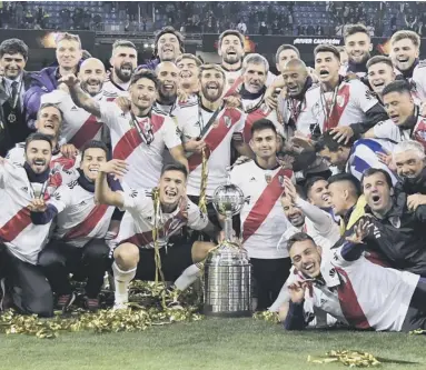  ??  ?? 0 River Plate players celebrate with the trophy after their Copa Libertador­es victory in Madrid last night.