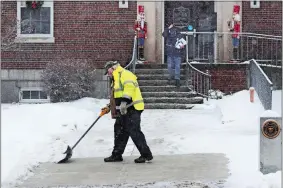  ?? CHARLES KRUPA/AP PHOTO ?? A worker shovels a coating of crusty snow from the walkway outside town hall during a snowstorm in Exeter, N.H., on Monday. The southern New Hampshire area received a coating of snow and ice during the winter storm.