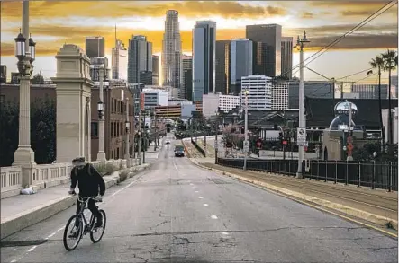  ?? Marcus Yam Los Angeles Times ?? A BICYCLIST RIDES along the First Street Bridge toward Boyle Heights during sunset in downtown Los Angeles.