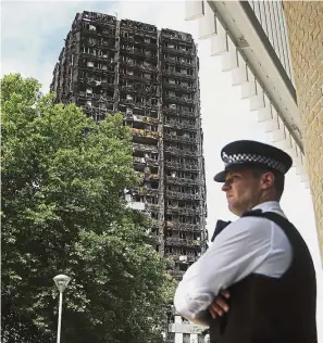  ??  ?? Cinder block: A police officer standing near the charred remains of the Grenfell Tower apartment building.
