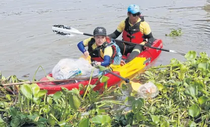  ?? PORNPROM SATRABHAYA ?? River clean-up Volunteers use canoe paddles to pick up rubbish in the Chao Phraya River near a pier in Nonthaburi yesterday. They are taking part in a campaign to educate the public about household waste management and garbage separation.