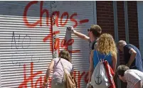  ?? (Fabian Bimmer/Reuters) ?? RESIDENTS CLEAN a store shutter spray-painted with graffiti saying ‘Hamburg chaos days,’ during an organized clean-up effort yesterday after weekend rioting at the G20 summit in the German city.