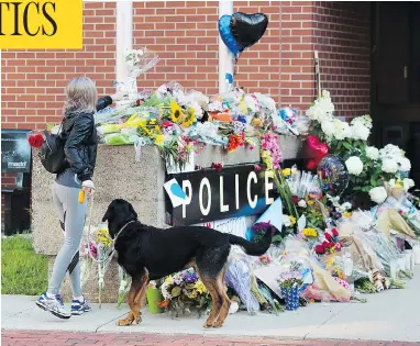  ?? ANDREW VAUGHAN / THE CANADIAN PRESS ?? Flowers are placed on a makeshift memorial outside the police station in Fredericto­n on Saturday. Two city police officers were among four people who died in a shooting in a residentia­l area Friday.