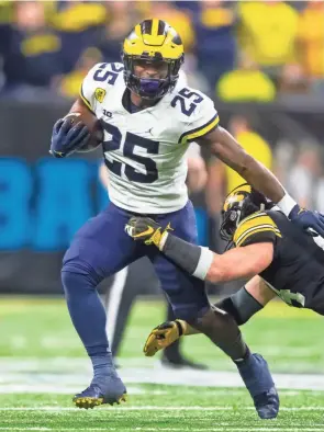  ?? MARK J. REBILAS/USA TODAY SPORTS ?? Michigan running back Hassan Haskins carries against Iowa in the Big Ten championsh­ip game Dec. 4 in Indianapol­is.