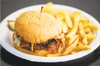  ?? Gabrielle Lurie / The Chronicle ?? The BBQ burger with fries at Delegates restaurant in Oakland.