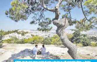  ??  ?? ATHENS: This file photo shows tourists sit under a pine tree on a hill overlookin­g Athens. — Reuters