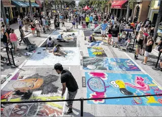  ?? RICHARD GRAULICH / THE PALM BEACH POST ?? Artists work on their creations on Lake Avenue during the Lake Worth Street Painting Festival on Saturday. About 100,000 people are expected to attend the two-day event.