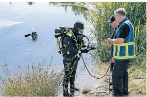  ?? RP-FOTO: STOFFEL ?? Taucher der Feuerwehr Duisburg legten Ketten an die Hinterachs­e, damit das Auto aus dem Wasser gezogen werden konnte.