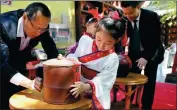  ?? JIANG DONG / CHINA DAILY ?? A girl and a boy (behind her) seal two pots of Anhua dark tea with mud and a piece of red paper during the recent tea-sealing ceremony in Beijing.