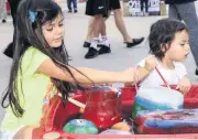  ??  ?? Addison, 4, left, and Avery Mankins, 2, try to free toys and shells from chunks of ice at the Moore Library during National Night Out.