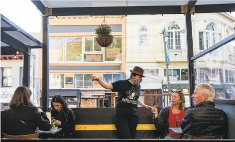  ?? Josie Norris / Special to The Chronicle ?? People sit in the parklet along Columbus Avenue at Devil's Acre bar in North Beach in S. F., which did not yet go into the purple tier.