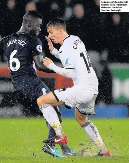  ??  ?? > Swansea’s Tom Carroll tangles with Tottenham defender Davinson Sanchez last night