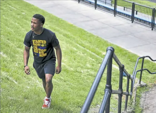  ?? Andrew Stein/Post-Gazette ?? Graduating senior Jeremiah Nash walks up the hill instead of taking the stairs from the Westinghou­se Academy football field. Football players have a tradition of never taking the stairs, so Jeremiah walks the hill “out of respect and tradition.”