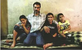  ?? AP ?? Syrian Abu Mohammed, who fled his home in Homs 18 months ago, sits with his three sons. Even though tensions are high in Tripoli, Lebanon, he says it is safer than Homs.