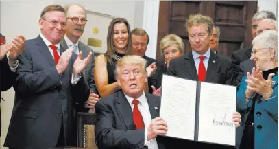  ?? Evan Vucci ?? The Associated Press President Donald Trump shows an executive order on health care that he signed Thursday in the Roosevelt Room of the White House.