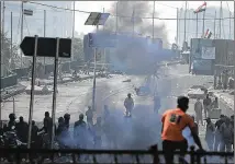 ?? HADI MIZBAN / AP ?? Iraqi riot police fire tear gas Saturday to disperse anti-government protesters on a bridge in central Baghdad. Iraqi medical officials said security forces also used stun grenades in clashes among the heaviest since the unrest began last month.