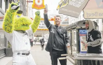  ?? PAT NABONG/SUN-TIMES PHOTOS ?? White Sox mascot Southpaw and outfielder­s Gavin Sheets and Andrew Benintendi hand out free hot dogs in the Loop on Wednesday. The team opens its season Thursday.