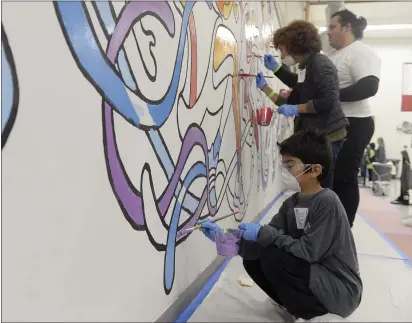  ?? PHOTOS BY JOEL ROSENBAUM — THE REPORTER ?? Izek Rentas, 11of Vacaville paints a portion of a mural on the walls of the gymnasium Monday at Fairfield High School. Izek was volunteeri­ng his time along with his mom and other staff members from Kaiser Permanente during the annual National Day of Service in honor of Dr. Martin Luther King Jr. Volunteers spread out across the campus in Fairfield to fix up the school taking on projects like outdoor landscapin­g, constructi­on of garden boxes, painting wall murals and interior cleaning classrooms.