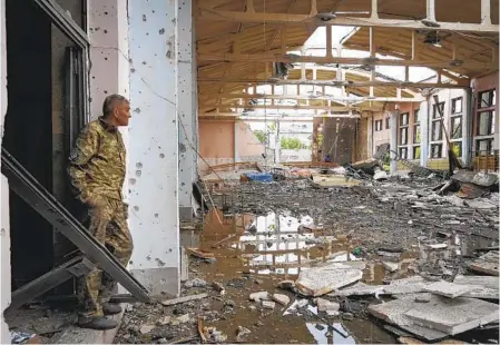  ?? ANDRII MARIENKO AP ?? A Ukrainian serviceman looks at the ruins Friday of the sports complex of the National Technical University in Kharkiv, Ukraine, damaged during a shelling. A military official said Ukrainian troops would pull out of the city of Sievierodo­netsk, a major loss for the military.