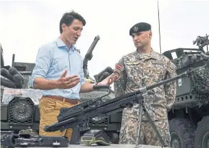  ?? ROMAN KOKSAROV/THE ASSOCIATED PRESS ?? Prime Minister Justin Trudeau speaks to a Latvian soldier on Tuesday. Trudeau says he has “continued, unflinchin­g support” for NATO, but refuses to raise Canada’s defence budget.