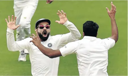  ?? / AFP / PETER PARKS ?? India's captain Virat Kohli celebrates with spin bowler Ravichandr­an Ashwin after beating Australia on day five of the first Test at the Adelaide Oval yesterday.