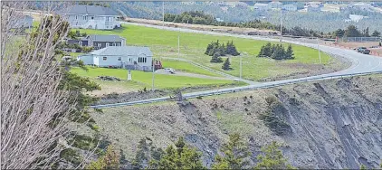  ?? GARY HEBBARD/SPECIAL TO THE TELEGRAM ?? A scenic view of the Outer Cove crash site. The home built by the United States government to replace the Stark's demolished home is at the left with a small, decorative lighthouse on the lawn. Payne's plane plunged over the cliff in the foreground.