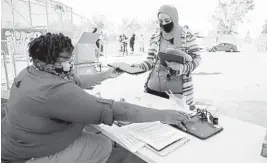  ?? JIM WILSON/THE NEW YORK TIMES ?? Velisa Woods, left, hands Chromebook­s to Faiza Ayesh on Monday, the first day of remote learning at an elementary school in Oakland, Calif. Ayesh has three children at the school.