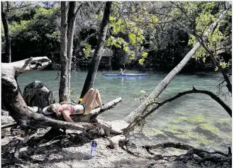  ?? DEBORAH CANNON / AMERICAN-STATESMAN ?? Kaycee Schairbaum finds a spot in the sun to enjoy Monday’s warmth at Barton Creek near Zilker Park. Unseasonab­ly warm temperatur­es have October still feeling like summer. A cold front will move into the area late in the week, bringing some relief.