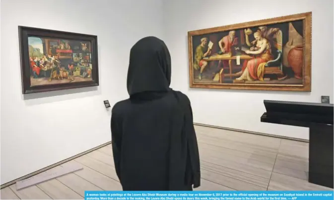  ??  ?? A woman looks at paintings at the Louvre Abu Dhabi Museum during a media tour on November 6, 2017 prior to the official opening of the museum on Saadiyat Island in the Emirati capital yesterday. More than a decade in the making, the Louvre Abu Dhabi...