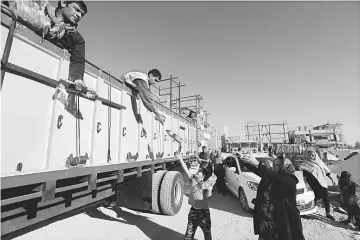  ??  ?? Members of the Iranian civil defence hand out bottles of water to survivors and residents in the town of Sarpol-e Zahab in Iran’s western Kermanshah province near the border with Iraq, following a 7.3-magnitude earthquake that left hundreds killed and...