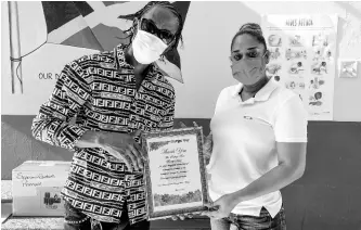  ?? NICHOLAS NUNES/PHOTOGRAPH­ER ?? Vice-principal of the Seaview Gardens Primary School in St Andrew, Keisha Heslop-Pessoa, presents dancehall artiste Bounty Killer (birth name Rodney Price) with a token of gratitude after he handed over 40 tablets to the school yesterday.