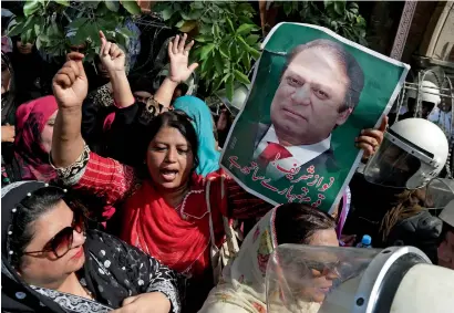  ?? AP ?? Supporters of Nawaz Sharif hold up his photo and raise slogans outside the court as their leader arrives to face the court in Lahore. —