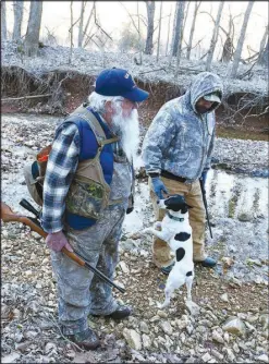  ?? Flip Putthoff/NWA Democrat-Gazette ?? Gary Wellesley (left), Chris Denham and squirrel dog Spec start their hunt Feb. 17 on a frosty morning.