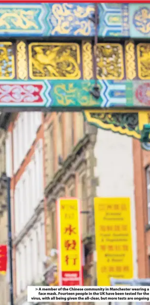  ??  ?? > A member of the Chinese community in Manchester wearing a face mask. Fourteen people in the UK have been tested for the virus, with all being given the all-clear, but more tests are ongoing