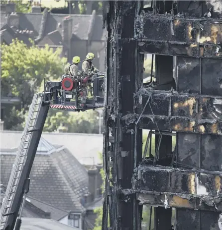  ?? PICTURE: GETTY ?? 0 Firefighte­rs perched on an extendable ladder inspect the remains of Grenfell Tower