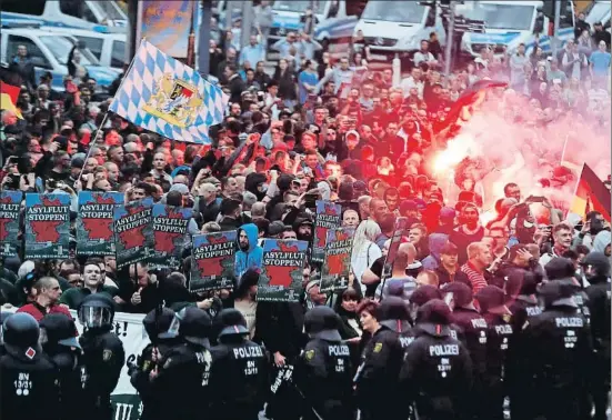  ?? ODD ANDERSEN / AFP ?? Manifestan­tes ultras con pancartas contra el asilo y bengalas encendidas frente al cordón policial, en su concentrac­ión el lunes en Chemnitz