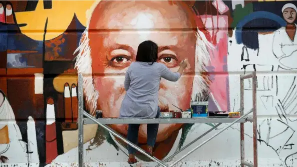  ?? AFP/VNA Photos ?? A REAL EYEFUL: Perched on a scaffold, 49-year-old Wijdan al-majed adds the final touches to a Baghdad mural dedicated to celebrated Iraqi poet Muzzafar al-nawab.