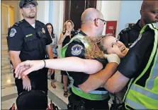  ?? [JACQUELYN MARTIN/THE ASSOCIATED PRESS] ?? Stephanie Woodward, of Rochester, New York, is removed from a sit-in Thursday at Senate Majority Leader Mitch McConnell’s office as she and other disability rights advocates protest proposed funding caps to Medicaid in the Senate’s health-care bill....