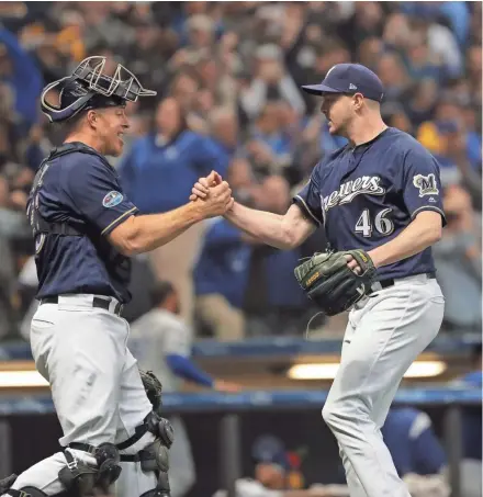 ?? MARK HOFFMAN / MILWAUKEE JOURNAL SENTINEL ?? Catcher Erik Kratz congratula­tes reliever Corey Knebel after the Brewers escaped with a victory Friday night at Miller Park in Game 1 of the National League Championsh­ip Series.
