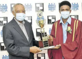  ??  ?? Former Member of Parliament for St James Southern Derrick Kellier (left) presents a trophy to valedictor­ian Antonio Bromley, the only male housekeepi­ng student from the Cambridge campus, during the recent CTEP graduation exercise in the constituen­cy.