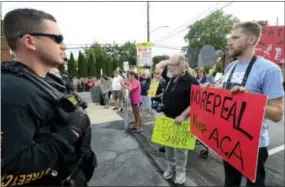  ?? MARC LEVY — THE ASSOCIATED PRESS ?? Watched by police, demonstrat­ors against the Senate Republican health care bill await the arrival of Pennsylvan­ia’s U.S. Sen. Pat Toomey outside the studios of WHTM-TV, Wednesday in Harrisburg. Toomey took questions in front of a live audience in...