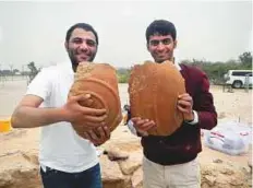  ??  ?? Ali Abdul Rahman Al Meqbali and Abdullah Khalfan Al Kaabi with fragments of the ancient jars unearthed in Sir Bani Yas.