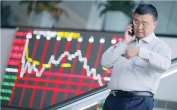  ?? — Reuters ?? A man talks on the phone inside the Shanghai Stock Exchange building at the Pudong financial district in Shanghai.