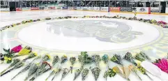  ?? JONATHAN HAYWARD / THE CANADIAN PRESS FILES ?? Flowers lie at centre ice at an April vigil to honour the victims of the fatal bus accident in Humboldt, Sask.