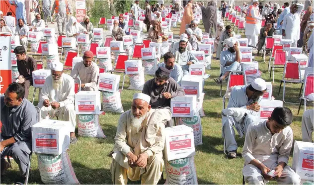  ?? Associated Press ?? ±
Volunteers from Al Khidmat Foundation distribute food and other items to flood victims in Shabqadar near Peshawar on Tuesday.