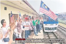  ??  ?? BERTOLAK: Awang Husaini dan Uda memegang bendera bersedia untuk pelepasan di Stesen Keretapi Putatan.